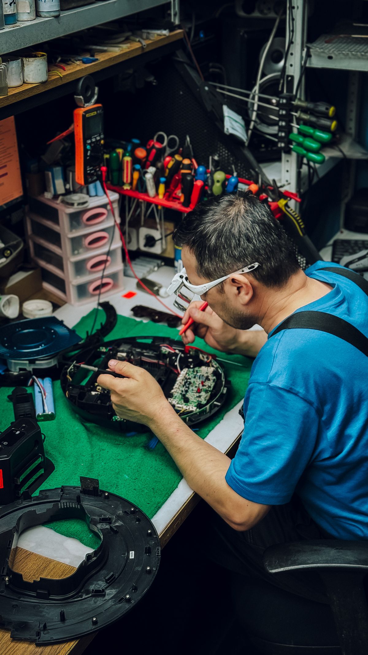 Tehničar popravlja elektroniku za radnim stolom u servisu